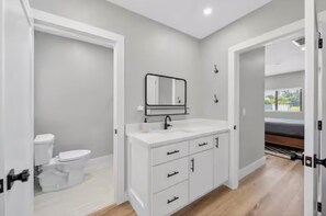 Ein modernes Badezimmer mit einem weißen Waschtisch, einem Spiegel und einer Toilette.