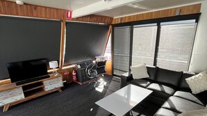 A modern living room with a flat-screen TV, a sofa, a coffee table, and a bicycle. - 3-bedroom house boat in beautiful Swan Reach with beautiful Murray River views. (Punyelroo)