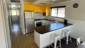 A compact kitchen with a central island, white bar stools, and a microwave. - 3-bedroom house boat in beautiful Swan Reach with beautiful Murray River views. (Punyelroo)