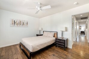 A bedroom with a bed, nightstands, a ceiling fan, and a hallway. - Spacious Family Home, 10 Min to Strip (Las Vegas)