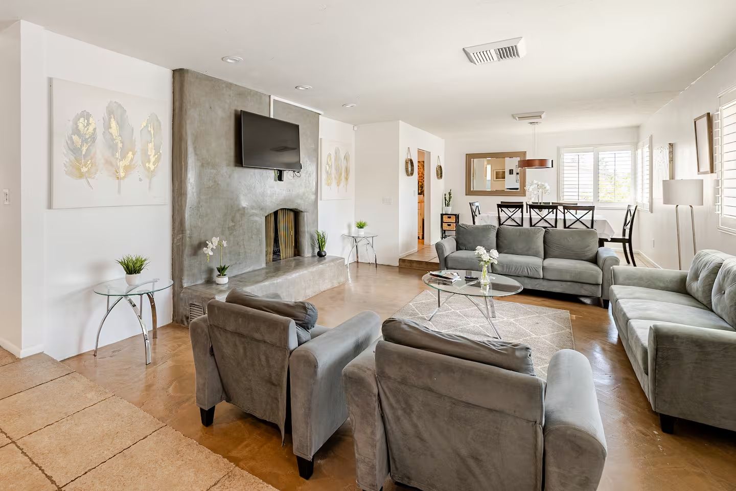 A modern living room with a fireplace, grey sofas, and a flat-screen TV.