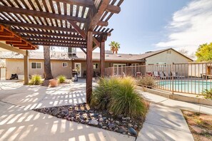 A residential backyard with a wooden pergola, a swimming pool, and a patio area. - Spacious Family Home, 10 Min to Strip (Las Vegas)