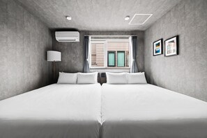 Ett modernt hotellrum med en stor säng, ett fönster med gardiner, en luftkonditioneringsanläggning och inramade tavlor på väggen.