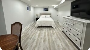 Un dormitorio con cama, cómoda, televisión y una mesita.