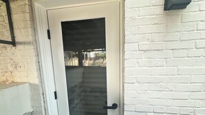 Una puerta blanca con un panel de vidrio, un picaporte negro y un escalón que lleva a la puerta.