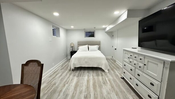 Un dormitorio con cama, cómoda, televisor y una silla.