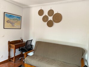 A room with a wooden desk, a black office chair, a beige sofa, and a wall-mounted woven decoration. - Family-friendly apartment 10 minutes from Comillas (pet-friendly) (el tejo, valdáliga)