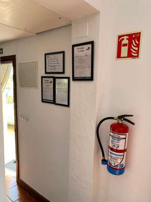 Ein Flur mit gerahmten Dokumenten an der Wand, einem an der Wand befestigten Feuerlöscher und einer Tür am Ende.