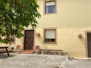 A building with a brown door, a window with a shutter, and a small bench. - Family-friendly apartment 10 minutes from Comillas (pet-friendly) (el tejo, valdáliga)