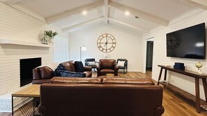 Ein Wohnzimmer mit Kamin, Ledersofas, einem Couchtisch und einer großen Wanduhr.