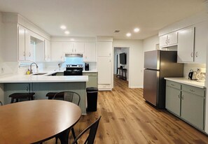 A modern kitchen with white cabinets, a central island, a stove, and a refrigerator. - Marblehead Executive Retreat (Jackson)