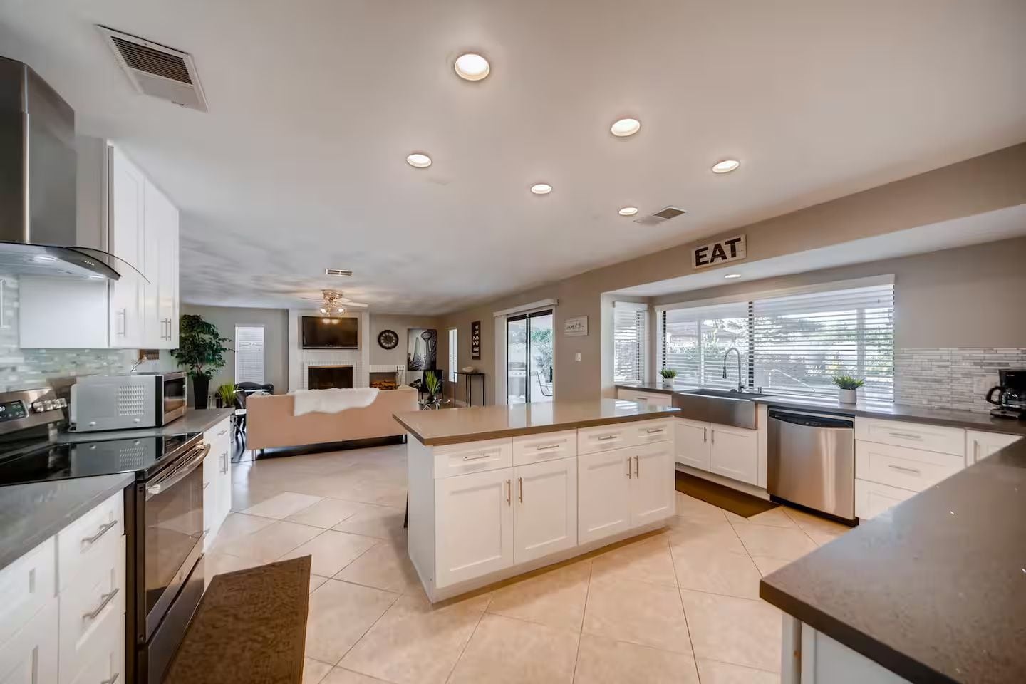 A modern kitchen with white cabinetry, a central island, and a built-in dishwasher.