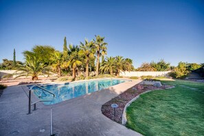 A swimming pool with a surrounding deck, palm trees, and a well-maintained lawn. - Family-Friendly Vegas Home, 10 Min to the Strip (Las Vegas)