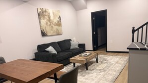 Uma sala de estar moderna com sofá, mesa de centro, mesa de jantar e tapete.