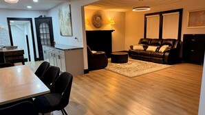 Uma sala de estar moderna com área de jantar, lareira e sofá de couro preto.