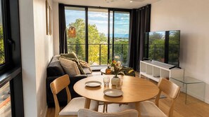 Ein modernes Wohnzimmer mit einer Couch, einem Esstisch, Stühlen und einem Fernseher.