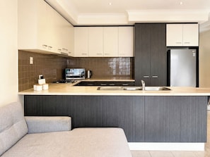 A modern kitchen with a central island, a built-in microwave, and a stainless steel refrigerator.