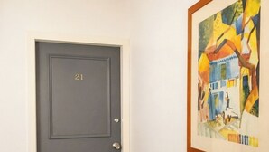 Eine geschlossene Tür mit der Nummer 21, ein gerahmtes abstraktes Gemälde an der Wand und ein Teppichboden.