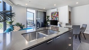 Une cuisine moderne dotée d’un grand îlot central, d’appareils électroménagers intégrés et offrant une vue sur l’extérieur.