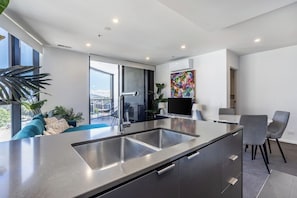 A modern kitchen with a large island, built-in appliances, and a view to the outdoors. - Elegant 3BR Retreat with Pool, Parking and Balcony (Phillip)