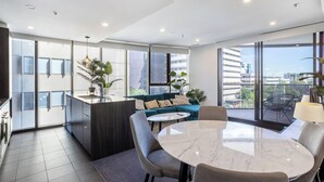 Un appartement moderne doté d’une cuisine, d’un coin repas et d’un balcon offrant une vue sur la ville.