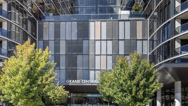 Un bâtiment moderne à la façade en verre, portant l’inscription « GRAND CENTRAL, 15, rue Bowes ».