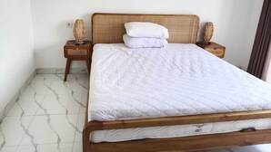 A single bed with a wooden frame and white bedding in a room with white walls and a tiled floor. - Cozzy Villa Sakangi Mas (Tabanan)