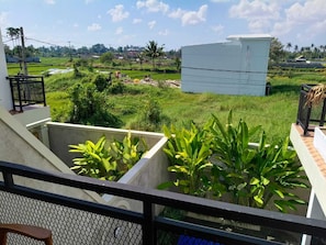 Een balkon met uitzicht op een groen veld en een wit gebouw.