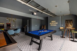 Ein Billardtisch in einem Raum mit Projektor an der Decke und einem Wandbild.