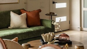 Una sala de estar con un sofá verde, una lámpara y una mesa de centro con adornos.