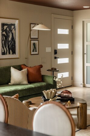 Ein Wohnzimmer mit einem grünen Sofa, einer Lampe und einem Couchtisch mit Dekoration.