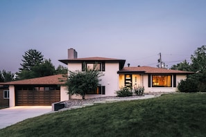 Una moderna casa a due piani con garage, un piccolo giardino anteriore e vialetto.