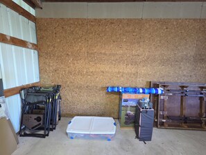 A storage room with a wooden wall, metal shelving, and various items including a folding wagon, a plastic container, and a blue fabric. - 3-bedroom house in lovely Frankfort with AC and charm (Frankfort)