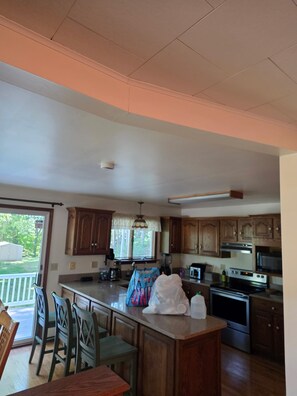 A spacious kitchen with wooden cabinets, a large island, and a dining area with chairs. - 3-bedroom house in lovely Frankfort with AC and charm (Frankfort)