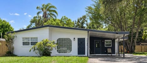 Ein Bungalow mit überdachter Veranda, Eingangstür und Garage.