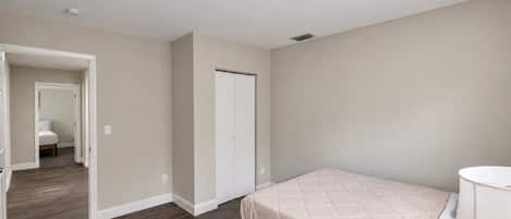 Un dormitorio con una cama, una mesita de noche y una puerta que da a otra habitación.