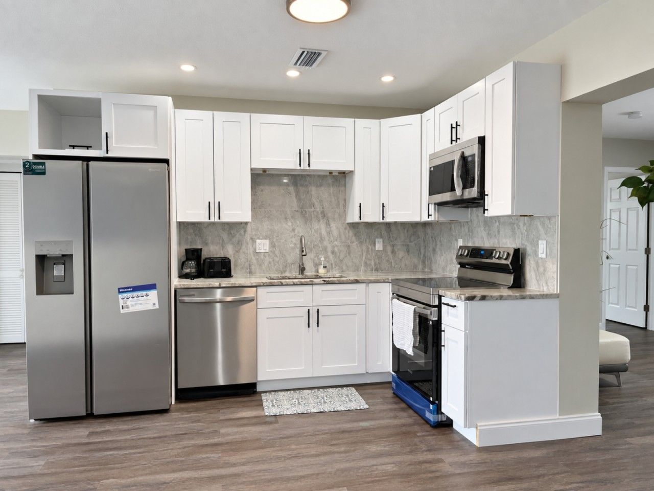 A modern kitchen with white cabinetry, stainless steel appliances, and a marble backsplash.
