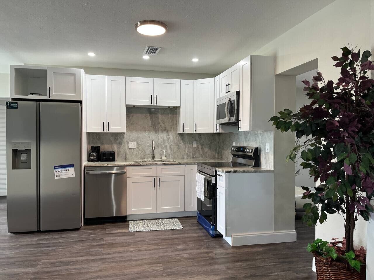 A modern kitchen with white cabinets, stainless steel appliances, and a central island.