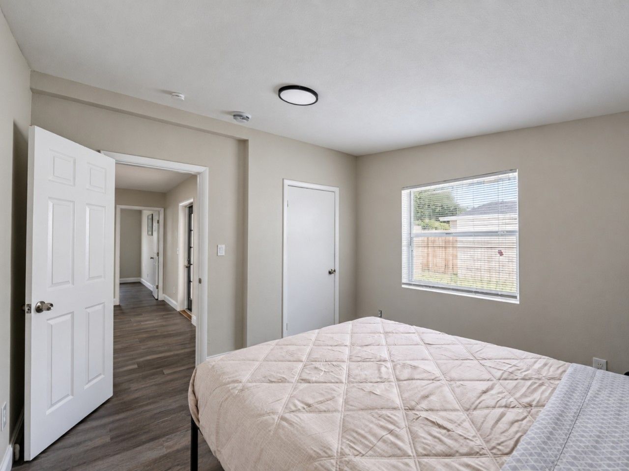 Un dormitorio con cama, ventana y puerta que da a otra habitación.