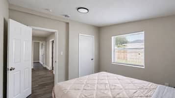 Un dormitorio con cama, ventana y puerta que da a otra habitación.