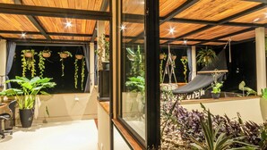 A modern interior with a large glass window, wooden ceiling, and various potted plants. - Con Amor Caribe · 2,500 sq ft · Jungle Villa · Wildlife at Your Door ·Near Beach (Manzanillo)