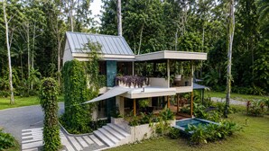 A modern two-story house with a flat roof, surrounded by lush greenery and a swimming pool. - Con Amor Caribe · 2,500 sq ft · Jungle Villa · Wildlife at Your Door ·Near Beach (Manzanillo)