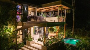 Ein modernes Haus mit Pool, Sitzgelegenheiten im Freien und üppiger Bepflanzung.