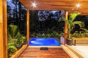 Une terrasse en bois qui mène à un jacuzzi offrant une vue sur une zone boisée.
