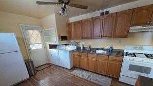 Una cocina con armarios de madera, estufa, lavaplatos y ventilador de techo.