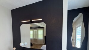 Una habitación con una pared oscura, una consola de madera, un espejo y una escalera.