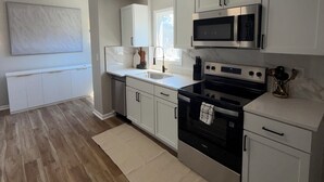 Una cocina moderna con armarios blancos, una estufa negra y un microondas.