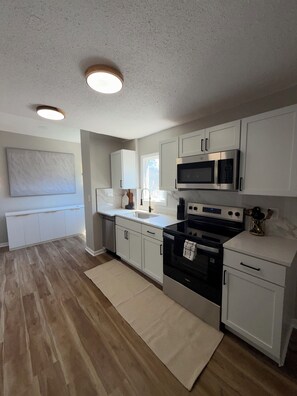 A modern kitchen with white cabinets, a black stove, and a microwave. -     Fully Remodeled 3Bed- 2 Bath  Home  Ideal for Extended Stays (Kansas City)