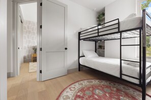 A room with a bunk bed, a door, a small table with a plant, and a patterned rug. - Relaxing Estate - Heated Pool - Near UT & Moody Center (Austin)