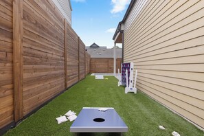 A backyard with a ping pong table, artificial grass, wooden fences, and a small shed. - Relaxing Estate - Heated Pool - Near UT & Moody Center (Austin)